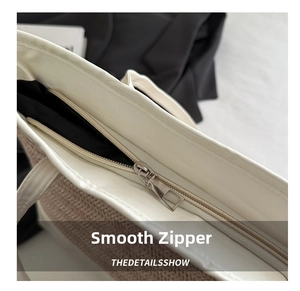 Close-up of smooth metal zipper and beige woven texture on large straw tote bag