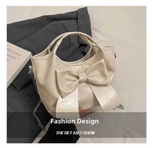 Detailansicht der cremeweißen Beuteltasche mit großer Schleife und dünner Metallkette