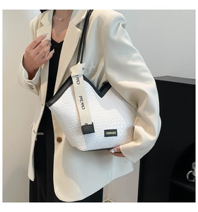 Détail du sac à bandoulière en cuir tressé blanc avec bordure noire et étiquette chic