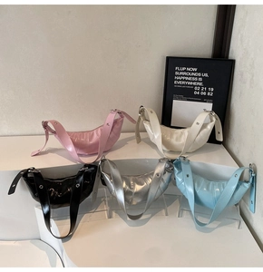 Five colored croissant bags displayed on steps with pleated patent leather textures
