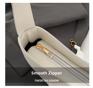 Detailed close-up of smooth gold zipper and hardware on white leather shoulder bag