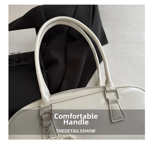 Detail of white leather handbag with faux pearl chain and silver ring hardware