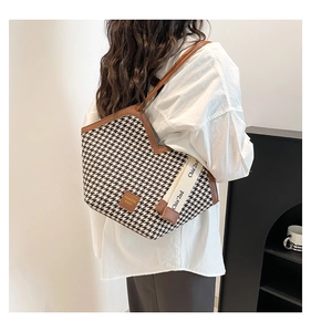 Detail view of houndstooth tote bag featuring leather trim and embroidered wide strap