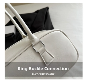 Detail of silver square buckle and textured off-white leather strap on a stylish handbag