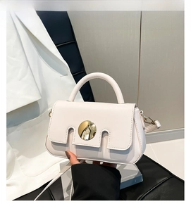 Detail of off-white small square bag with golden round buckle and arched top handle