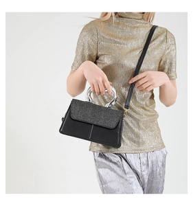 Détail du sac à bandoulière avec rabat à paillettes et poignée métallique sur mannequin
