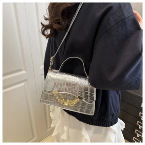 Silver crocodile-textured bag with golden chain and shoulder strap on model