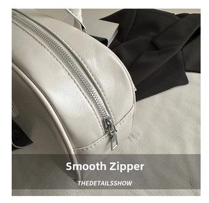 Detailed close-up of smooth silver metal zipper and faux leather texture on pillow bag