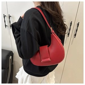 Shoulder shot of a red half-moon saddle bag showing the smooth faux leather and curved design