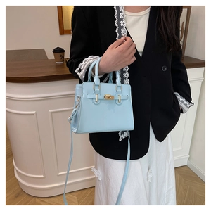 Light blue faux leather handbag with gold lock shown in a casual lifestyle setting