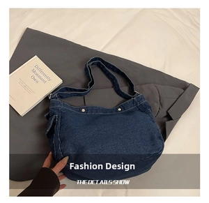 Detail of blue denim hobo bag featuring contrast white stitching and wide shoulder strap