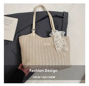 Close-up of woven straw tote bag featuring leather handles and a white lace bow charm