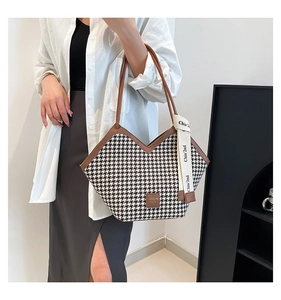 Detailed shot of houndstooth tote bag with brown leather trim and stylish logo detail