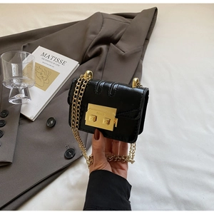 Détail d'un mini sac bandoulière noir avec chaîne dorée et fermoir carré en métal