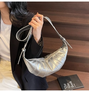 Detail of silver metallic croissant bag with pleated texture and adjustable strap