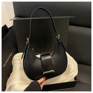 Detail of black crescent hobo bag with gold buckle on luxury silk cloth and gift box
