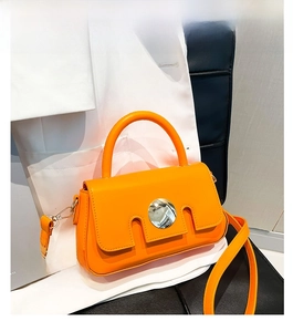 Detail of elegant orange crossbody bag with gold round metal buckle and top handle