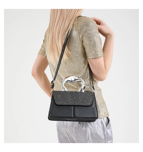 Détail d'un sac à main en cuir noir avec rabat à paillettes et poignée en métal argenté