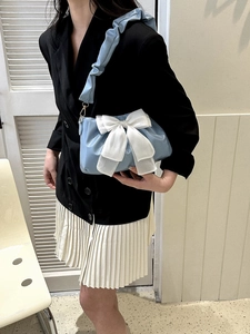 Light blue shoulder bag with large white satin bow and ruffled strap on female model