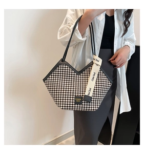 Detail of checkered tote bag with leather trim and decorative lettered ribbon strap