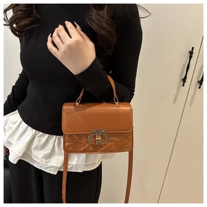Detail view of caramel brown crossbody bag with metallic clasp and quilted texture