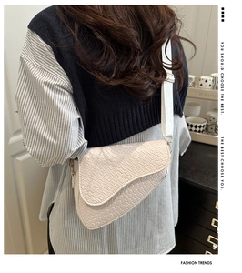 Detail of white crocodile embossed saddle bag with adjustable wide strap on shoulder