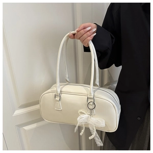 Detail of off-white minimalist bowling bag with pearl lace bow charm and long leather handles