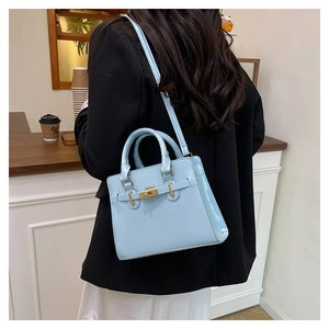 Detailed view of light blue glossy leather handbag with gold twist lock and strap