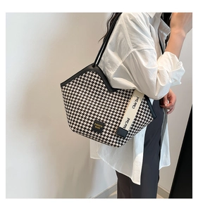 Close-up of houndstooth tote bag with wide logo shoulder strap shown on a model
