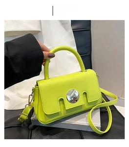 Close-up of a neon green leather crossbody bag featuring a large silver circular metal lock