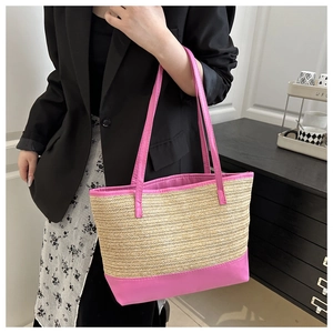 Detail of a beige woven straw tote bag with vibrant pink leather trim shown on model