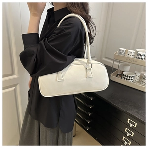 Close-up of minimalist white leather pillow bag with gold hardware on a model