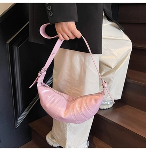 Close-up of pink quilted crescent bag with shiny patent leather and silver buckles