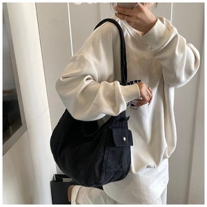 Dettaglio di una borsa hobo in denim nero con tasca laterale e fibbia in metallo su modella
