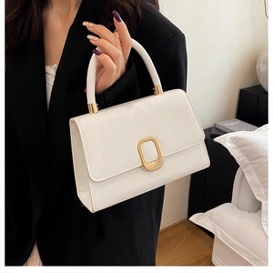 Detailed shot of white faux leather handbag with elegant gold buckle and structured handle