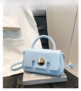 Detail of light blue PU leather handbag featuring a prominent gold round buckle closure
