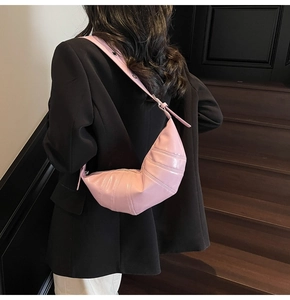 Detail of pink crescent bag with horizontal pleats and adjustable strap on model