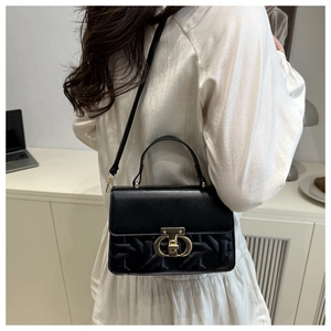 Detail of elegant black bag featuring gold twist lock and textured woven pattern
