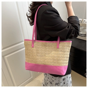 Detail of straw woven tote bag featuring vibrant pink trim and slim shoulder straps