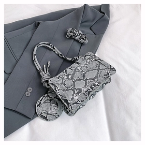 Détail du sac bandoulière à imprimé serpent avec pochette ronde sur blazer gris