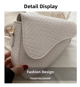 Detailed view of white saddle bag with crocodile texture and gold ring metal hardware