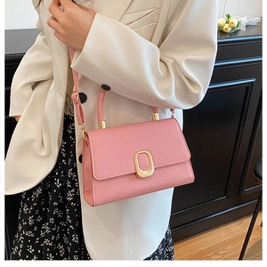 Close-up of pink crossbody bag featuring a golden oval metal lock and matching leather handle
