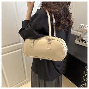 Close-up of beige cylindrical shoulder bag showing leather texture and silver hardware