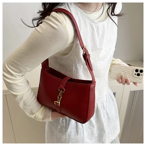 Detail of red leather Jackie style shoulder bag with gold piston clasp and adjustable strap