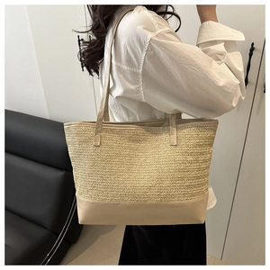Detail of hand-woven straw tote with smooth beige shoulder strap texture and craftsmanship