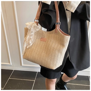 Detail of straw tote bag with pink leather handles and delicate white lace bow accent
