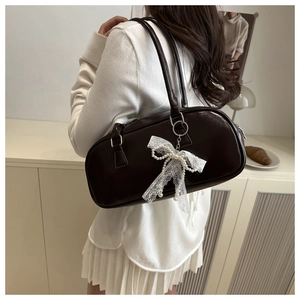 Detail of dark brown leather shoulder bag with white lace bow and pearl pendant