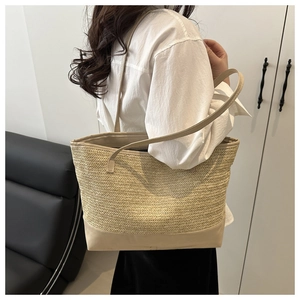 Detail of straw woven tote bag with beige shoulder strap worn by a model in lifestyle setting