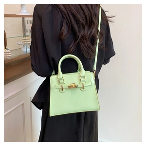 Close-up of mint green leather handbag featuring gold clasp and belt detail on a model