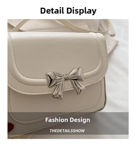 Close-up of elegant silver bow buckle on creamy white faux leather shoulder bag